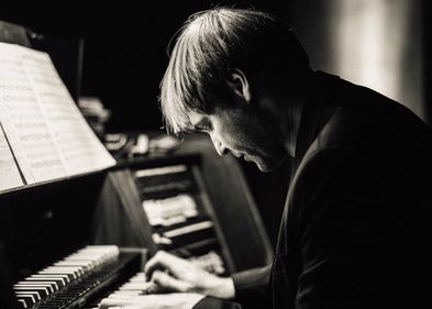 Schwarz-Weiß-Fotografie von Daniel Beilschmidt an seiner Orgel sitzend und spielend
