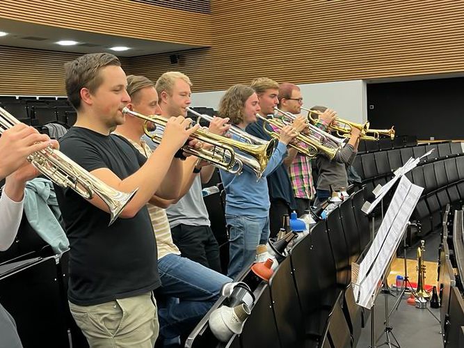 Mehrere Trompetenspieler üben im Hörsaal der Universität.